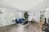 Elegant living room with modern decor, featuring a stylish blue sofa, plush white armchair, and sleek coffee table on hardwood floors.