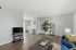 Modern living room with sleek hardwood floors, cozy blue couch, and a stylish open dining area. Bright and inviting space complemented by a chic shelving unit and elegant decor.