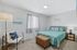 Bright and inviting bedroom with modern decor, featuring a cozy double bed, decorative wall art, and a stylish reading nook with a chic floor lamp.
