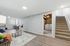 Bright and inviting basement living area with sleek flooring, cozy seating, and convenient laundry room.