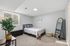 Inviting bedroom with a plush bed, chic decor, large mirror, and bright window lighting in a stylish apartment.