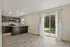 Bright open-concept kitchen and dining area featuring modern dark wood cabinetry, stainless steel appliances, and large sliding glass doors leading to a serene outdoor view.