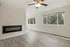 Bright and spacious living area featuring a modern fireplace and large windows with a lush forest view.