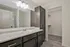 Modern bathroom with sleek dark cabinetry, marble countertop, and spacious walk-in closet.