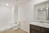 Modern bathroom with sleek fixtures, featuring a large mirror, elegant vanity, and spacious shower area.