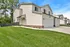 Charming modern duplex with pristine white facade, lush green lawn, and cozy front porch, ideal for family living.