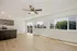Bright and modern open-plan kitchen and living area with large windows overlooking lush greenery, featuring sleek cabinetry and stainless steel appliances.