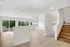 Bright and airy open-concept living area with large windows offering scenic views, featuring sleek wooden flooring and a modern staircase.