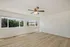 Bright and spacious living room with wide windows and elegant hardwood flooring, offering stunning views of lush greenery.