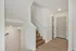 Elegant interior hallway featuring modern wooden staircase and stylish neutral walls, creating a warm and inviting entryway.