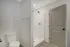 Sleek, modern bathroom featuring a pristine shower, elegant toilet, and stylish door in a bright, minimalist setting.