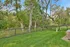 Serene backyard featuring lush green grass and mature trees, perfect for relaxation and privacy.