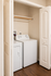 Cozy laundry nook featuring a washing machine and dryer with elegant white cabinetry and rich wood flooring.