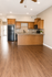 Modern kitchen with elegant wood flooring and cabinetry, featuring a sleek black refrigerator and stove, ideal for culinary enthusiasts.