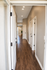 Inviting hallway of a modern apartment, showcasing sleek hardwood floors, recessed lighting, and elegant door finishes.