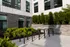 Modern apartment exterior with sleek black brickwork, abundant green landscaping, and convenient bike racks, offering urban living appeal.
