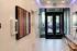 Modern apartment lobby featuring vibrant abstract art and sleek double glass doors, inviting ample natural light.