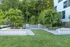 Charming outdoor space featuring lush greenery, modern architecture, and a cozy seating area with BBQ grills.
