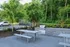 Beautiful outdoor patio with sleek picnic tables and a modern barbecue grill, surrounded by lush greenery.