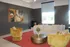 Contemporary living room with bold abstract art, lush mustard armchairs, and a cozy white sofa on a vibrant red rug.