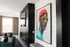 Chic modern living room with vibrant artwork and plush green seating, featuring floor-to-ceiling windows and elegant neutral drapes.