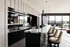 Elegant modern kitchen with sleek black cabinetry, marble countertops, and stylish pendant lighting, offering panoramic views through large glass doors.