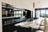 Luxurious modern kitchen with sleek black cabinets, elegant marble countertops, and stylish bar seating overlooking panoramic views.