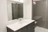 Sleek modern bathroom featuring a spacious walk-in shower, elegant vanity with ample storage, and a large mirror.