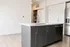 Modern kitchen featuring a sleek island with a stainless steel faucet and built-in dishwasher, set against elegant light wood flooring and contemporary stainless steel appliances.