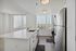 Modern kitchen with sleek stainless steel appliances, white countertops, and panoramic city views through large windows.