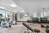 Bright and modern in-building gym featuring state-of-the-art exercise equipment, weights, and a wall-mounted TV for an energized workout experience.