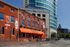 Vibrant cityscape showcasing an inviting bar and grille with eye-catching signage and a modern tower in the background.