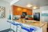 Modern kitchen with granite countertops, sleek wood cabinets, and vibrant blue bar stools.