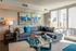 Modern urban living room with a stylish gray sofa, colorful abstract artwork, and floor-to-ceiling windows offering a vibrant city view.