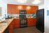 Modern kitchen with elegant wooden cabinetry, sleek black appliances, and beautiful granite countertops offering a stylish and functional cooking space.