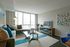 Bright and modern living room featuring a chic sectional sofa, glass coffee table, and stylish decor with large windows offering city views.