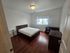 Inviting bedroom with elegant wooden flooring, cozy lighting, and a large window that fills the room with natural light.