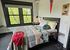 Bright and inviting bedroom featuring a comfortable, modern bed with colorful geometric bedding, large window with scenic views, and stylish decor.