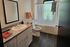 Modern bathroom with elegant grey tile flooring, sleek white vanity, and serene natural light from a large window above the bathtub.
