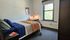 Cozy bedroom with a large window, well-lit workspace, and modern decor, perfect for relaxation and productivity.