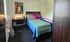 Cozy bedroom showcasing a stylish bed with colorful bedding, a functional desk with a lamp, and modern decor.