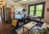Charming open-plan apartment living room with modern kitchen, cozy seating, and large windows overlooking greenery.