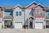 Charming townhouse exterior with modern architecture, featuring two-tone siding and private garages, bathed in bright sunlight.