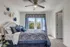 Elegant bedroom with plush bedding and floral accents, large window offering lush greenery views.