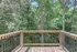 Charming wooden deck with a serene view of lush green forest, perfect for relaxation and nature lovers.