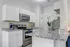 Modern kitchen featuring sleek granite countertops, white cabinetry, and stainless steel appliances, accented by fresh flowers and a stylish coffee maker.