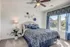Elegant bedroom with plush blue and white decor, featuring a ceiling fan and large window with a scenic view.