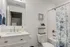 Bright and modern bathroom featuring a sleek white vanity with marble countertop, elegant floral shower curtain, and stylish decor accents.