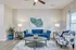 Bright and elegant living room featuring a plush blue velvet sofa, floral armchair, and modern decor creating a cozy ambiance.