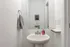Chic powder room with a modern white sink, elegant mirror, and tastefully decorated accents showcasing minimalist elegance.